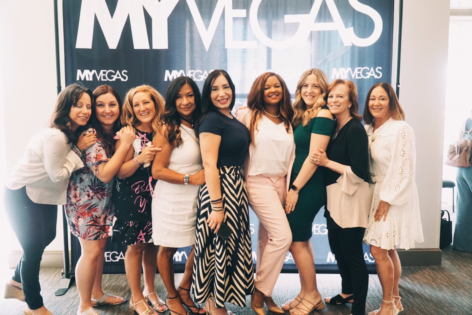 Women smiling together at the OWN IT event photo wall